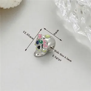 Macro detail of enamel skull charm with blue gemstone and floral pattern dimensions