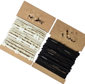 Dettaglio di elastici per capelli intrecciati neri e beige su supporto di cartone