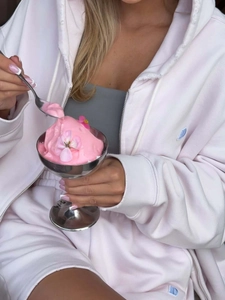 Détail d'un sweat à capuche rose en coton avec broderie bleue et finitions des poignets usées