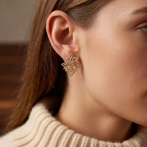 Elegant 18k gold plated fleur-de-lis earrings with cubic zirconia on female model