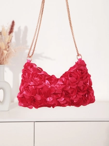 Detail of rose red satin evening bag featuring 3D floral petals and a gold chain strap