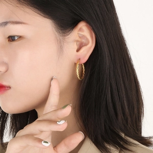 Close-up of model wearing elegant golden twisted rope texture hoop earrings for women