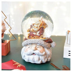 Detail of Christmas snow globe with Santa base and miniature sleigh in glass ball