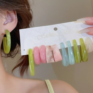 Gros plan de boucles d'oreilles créoles en résine acrylique aux tons pastel variés