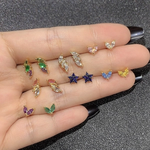 Detailed macro view of colorful zircon star and geometric stud earrings held by hand