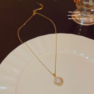 Close-up of a golden sunflower pendant with zircon crystals on a delicate O-chain