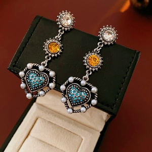 Detail of vintage flower earrings with crystal accents and pearls on a jewelry box
