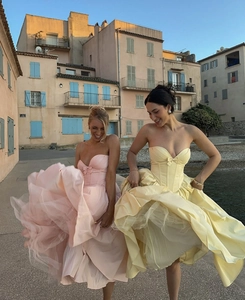 Detail of the elegant bow bodice and flowing pleated hem on pink and yellow tube dresses
