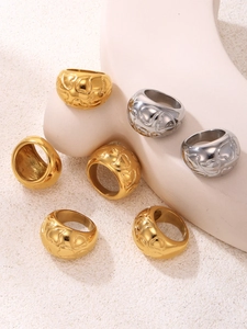 Detailed view of high-polished gold and silver heart-embossed rings on minimalist props