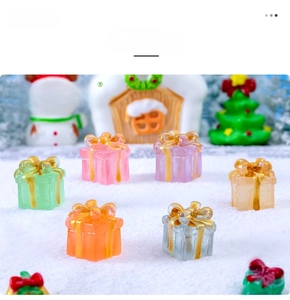 Miniature glowing Christmas gift box figurines with golden bows on snowy background