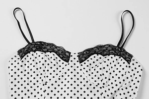 Detail of white polka dot top featuring black lace trim and delicate thin straps