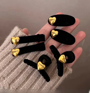 Dettaglio di fermagli per capelli neri floccati con ciondoli a cuore d'oro e incisione