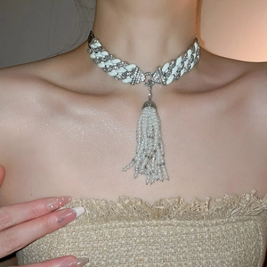 Detailed view of luxury choker necklace with white enamel links and diamond tassel