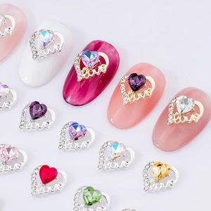 Nahaufnahme von Herz-Nagelkunst-Anhängern aus Legierung mit Love-Schriftzug und Kristallen