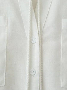 Close-up of V-neck cotton linen shirt with braided trim and white round buttons