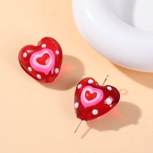 Macro shot of red heart-shaped glass bead with pink center and white polka dots