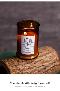 Macro shot of a lavender scented soy candle in a brown glass jar on a rustic wood base