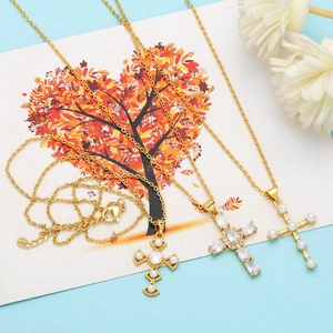 Detailed macro view of gold cross necklaces with pearls and zircons on decorative card