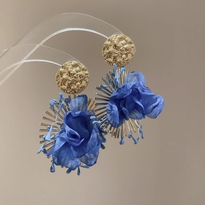 Close-up of blue chiffon flower earrings with textured gold metal studs and petals