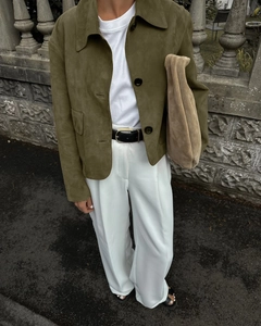 Detail view of olive green suede jacket with buttons and collar on a model
