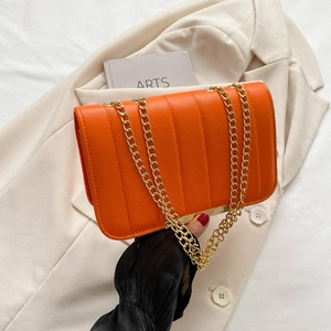 Orange PU leather chain shoulder bag with vertical quilting on a white blazer