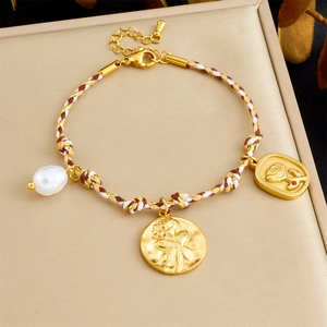 Detailed macro of gold rose pendants and irregular pearls on a woven bohemian bracelet