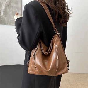 Caramel brown soft leather hobo bag with silver zippers shown from a side perspective