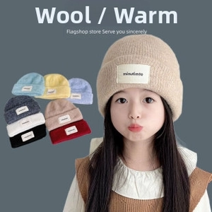 Detail showing colorful knitted wool beanies for children with branded logo patch