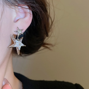 Macro shot of silver star drop earrings with sparkling cubic zirconia on a female model
