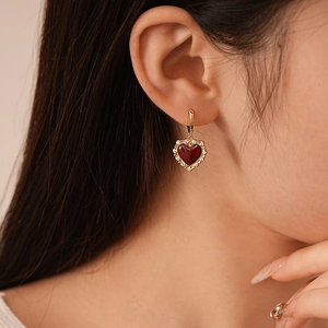 Close-up of vintage heart drop earrings in burgundy enamel with gold plating and zircons