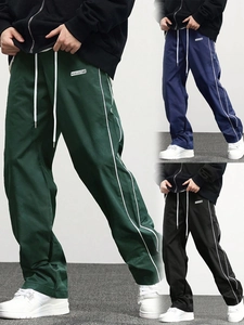 Detail view of woven street joggers showing elastic drawstring waist and side stripes