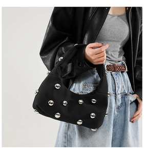 Detail of black underarm bag featuring large silver metal studs and punk style texture