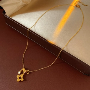 Close-up of 18k gold plated clover pendant with zircon on soft white silk fabric