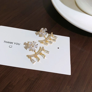 Macro detail of gold flower earrings with zircon petals and curved droplet tassels
