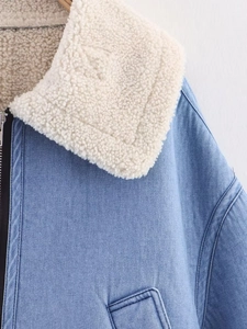 Close-up of blue denim jacket showing thick white faux shearling collar and zipper detail
