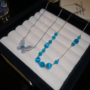 Detail of silver butterfly pendant and cat-eye stone necklace in a gift box