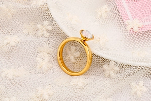 Dettaglio di un anello dorato in acciaio inossidabile con gemma sfaccettata su pizzo