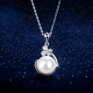 Elegant white pearl pendant necklace with clover silver clasp and zircons on blue background