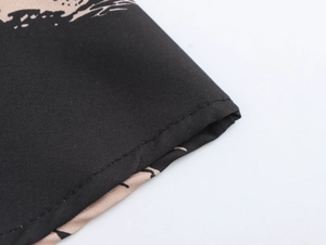 Detail of double-stitched hem and wave print pattern on black fabric of the dress