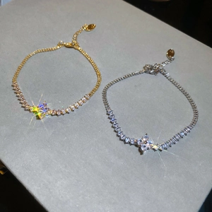 Detail of gold and silver butterfly floral bracelets with sparkling zircon cross charms