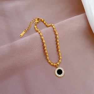 Detailed close-up of gold beaded bracelet with a black agate pendant and crystal halo