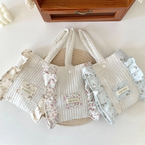 Close-up of three quilted floral wrist bags with ruffled edges and snap buttons
