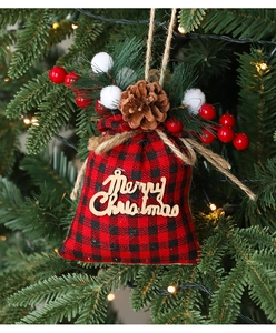 Detail of red and black plaid Christmas gift bag with wood 'Merry Christmas' tag on tree