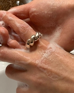 Detailed close-up of a twisted silver-plated rope ring being washed with soap foam