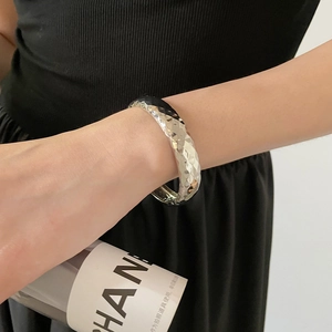 Vue détaillée d'un bracelet manchette argenté avec texture géométrique facettée sur modèle