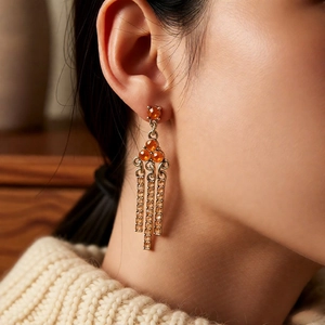 Close-up of vintage orange rhinestone triangle tassel earrings worn by a female model