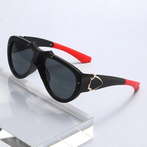 Detail of black sunglasses with red temples and a gold shield metal accent on the hinge