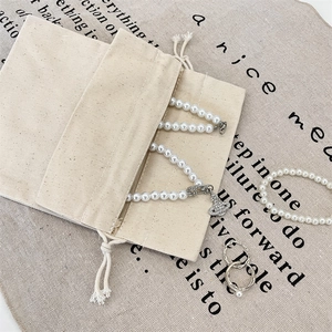 Detail of Saturn orb pearl necklace and ring set with drawstring canvas jewelry pouch