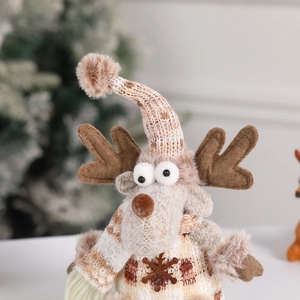 Knitted Christmas reindeer doll ornament with snowflake details on a festive tree background