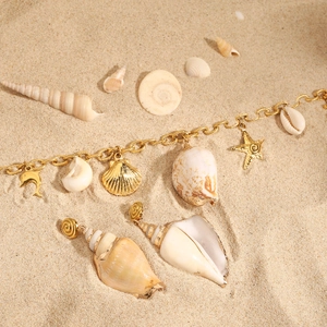 Détail d'un ensemble collier doré thème plage avec étoiles de mer et coquillages naturels